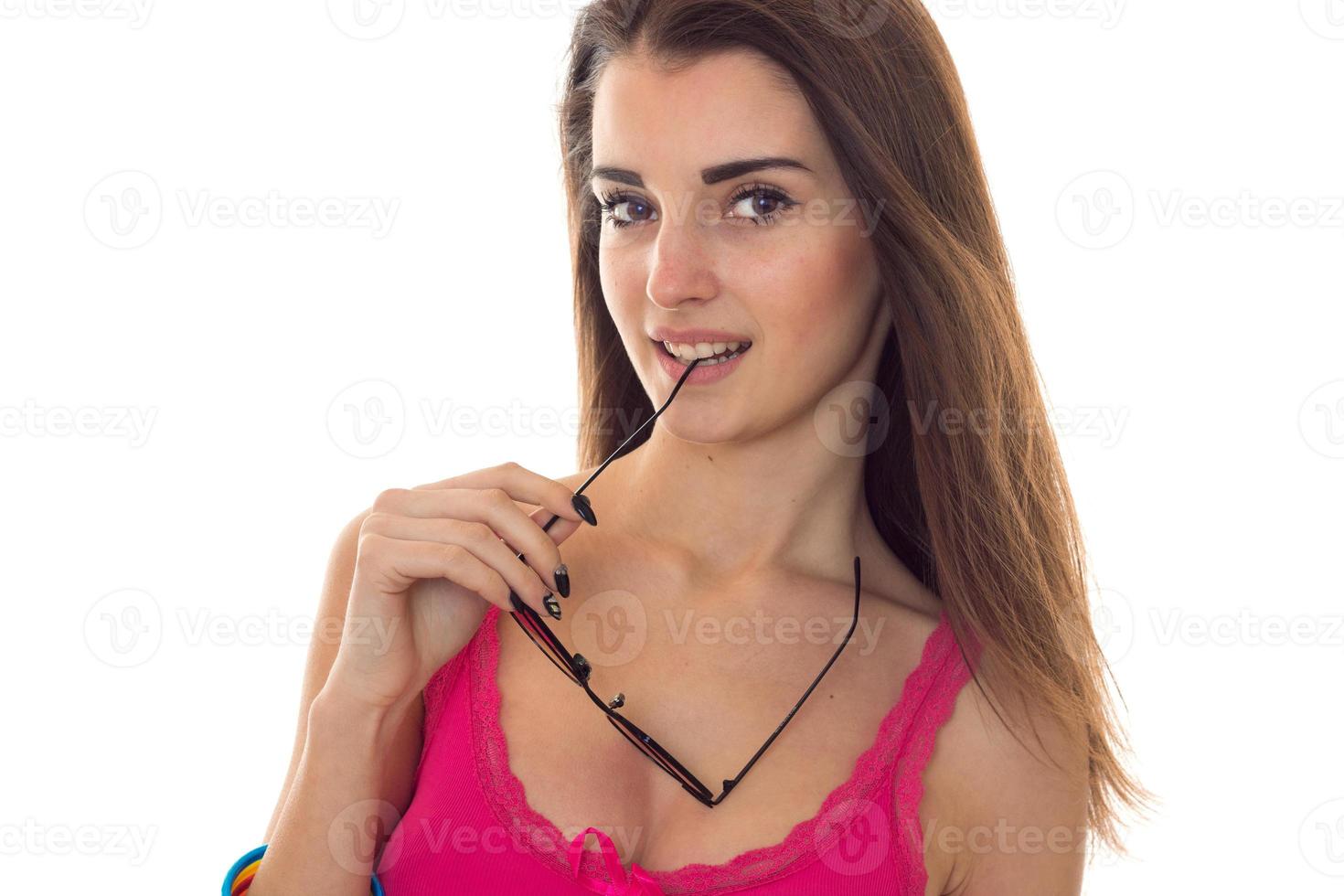 young seductive brunette girl in pink shirt sexually take in the mouth sunglasses isolated on white background photo