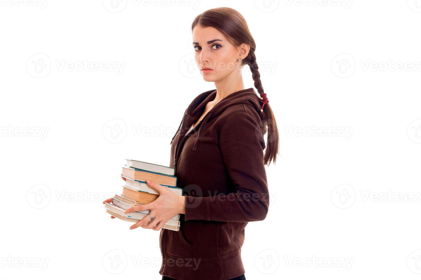 young girl with thoughtful person stands sideways and holding books photo