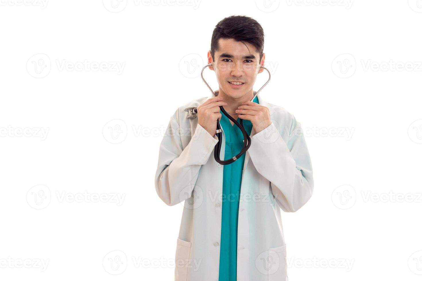 a young doctor in a white lab coat stethoscope into his ears and smiling isolated on white background photo