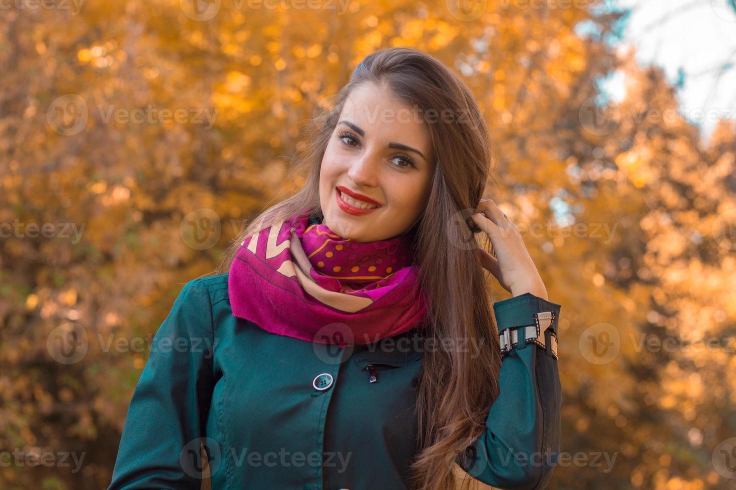 linda chica con un pañuelo alrededor del cuello sonríe y se para en la calle foto