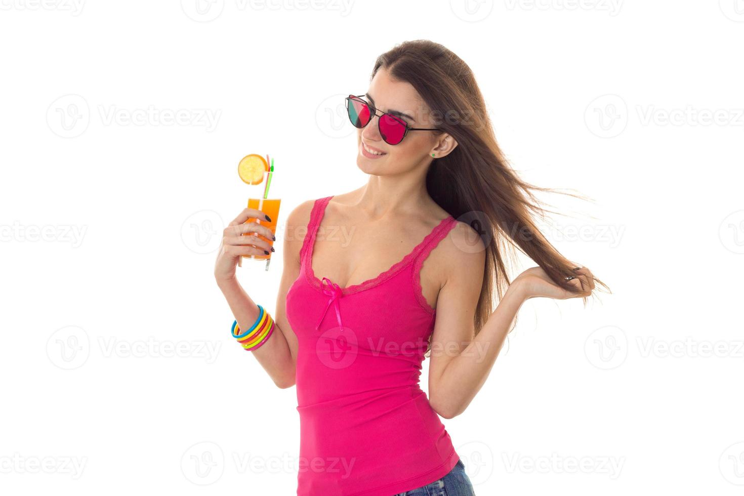 hermosa chica moldaja con una camiseta brillante y gafas de sol se pone de lado y sostiene un vaso de jugo foto