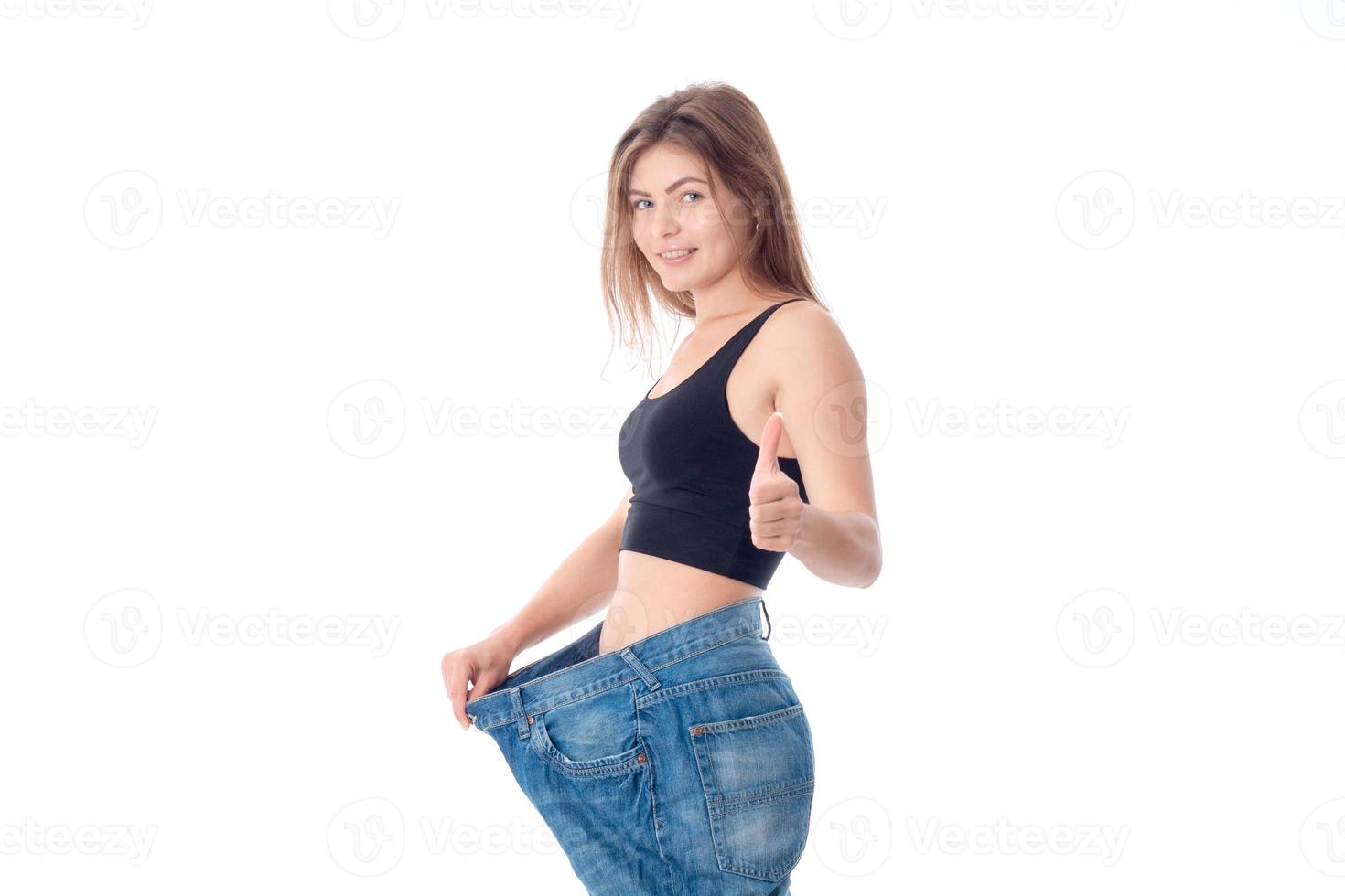 slender girl stands sideways in big pants and shows the class of isolated on white background photo