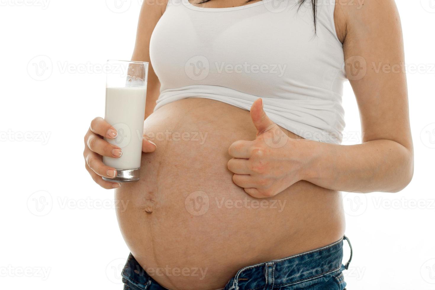 close up of pregnant woman with glass of milks showing thumbs up isolated on white background photo