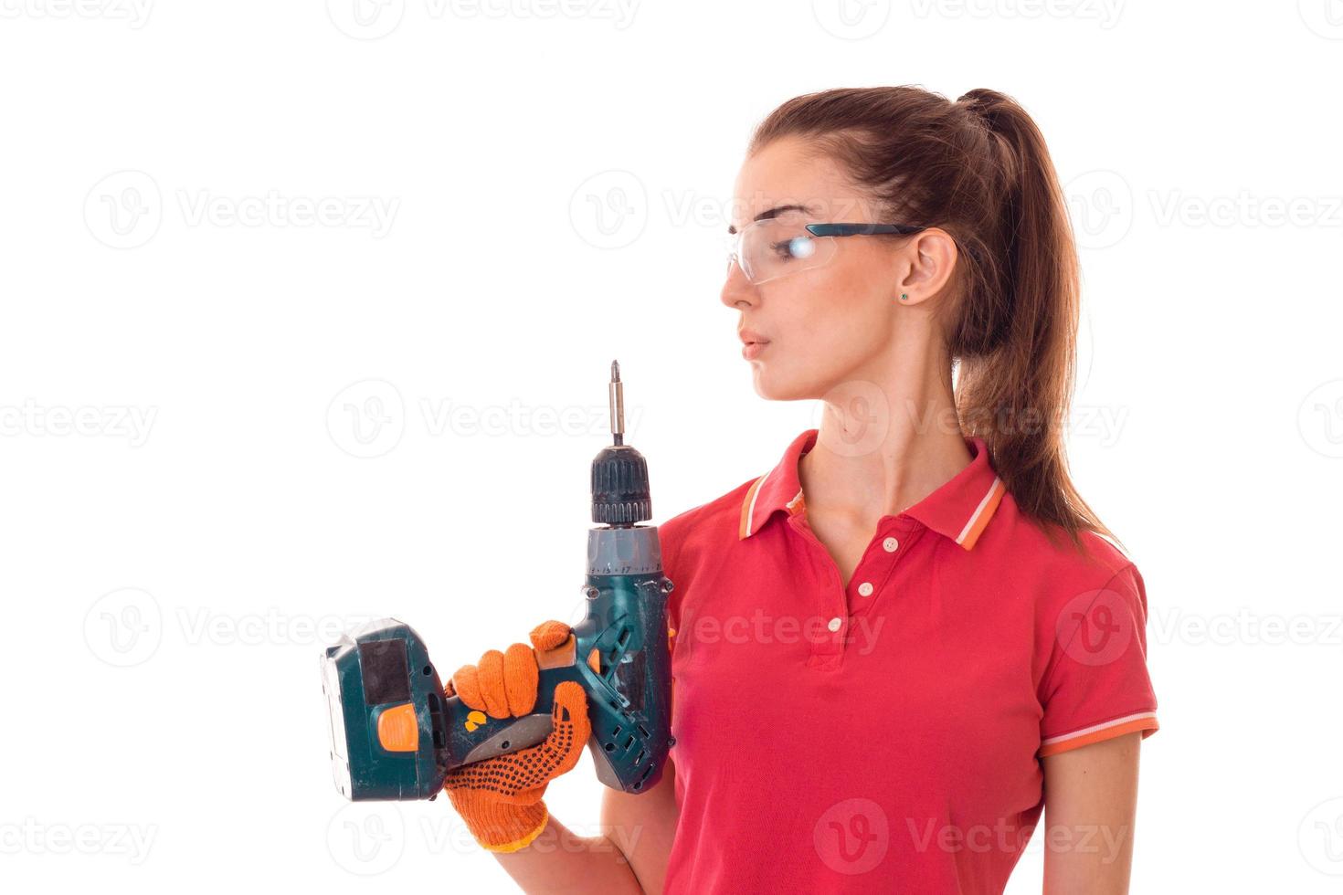 a young girl is worth turning sideways to the camera and holding a drill to repair photo