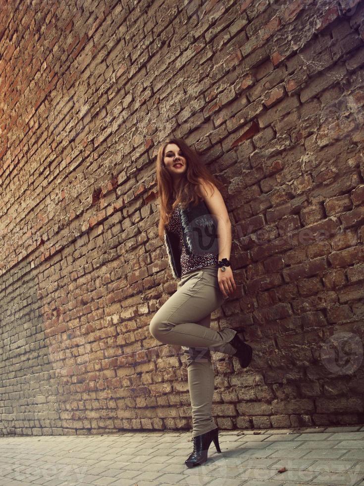 Cute girl with long red hair stand near brick wall photo