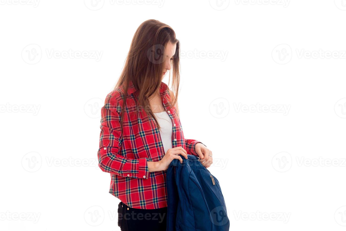 Atractiva joven estudiante morena adolescente con ropa elegante y mochila en las manos posando aislada de fondo blanco foto