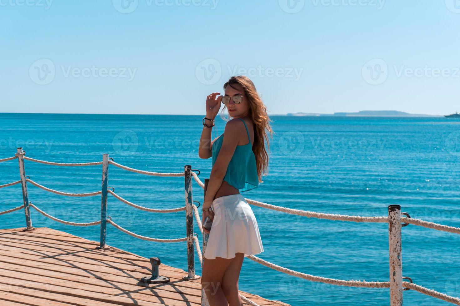 young blonde girl posing on pier with seascapeon background photo