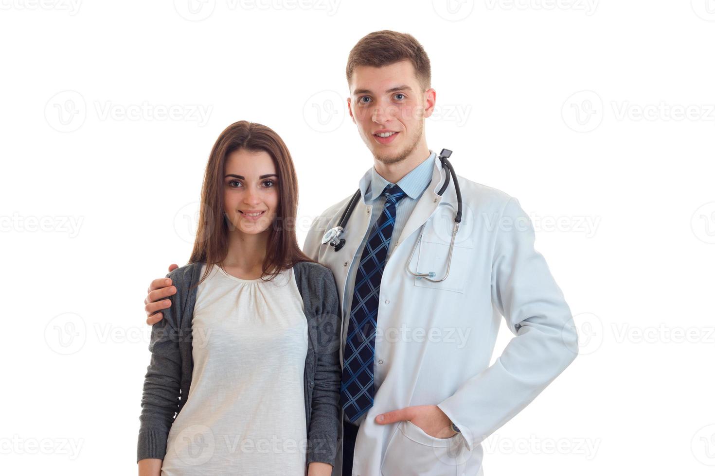 young handsome doctor in a white lab coat stands next to a cute girl photo