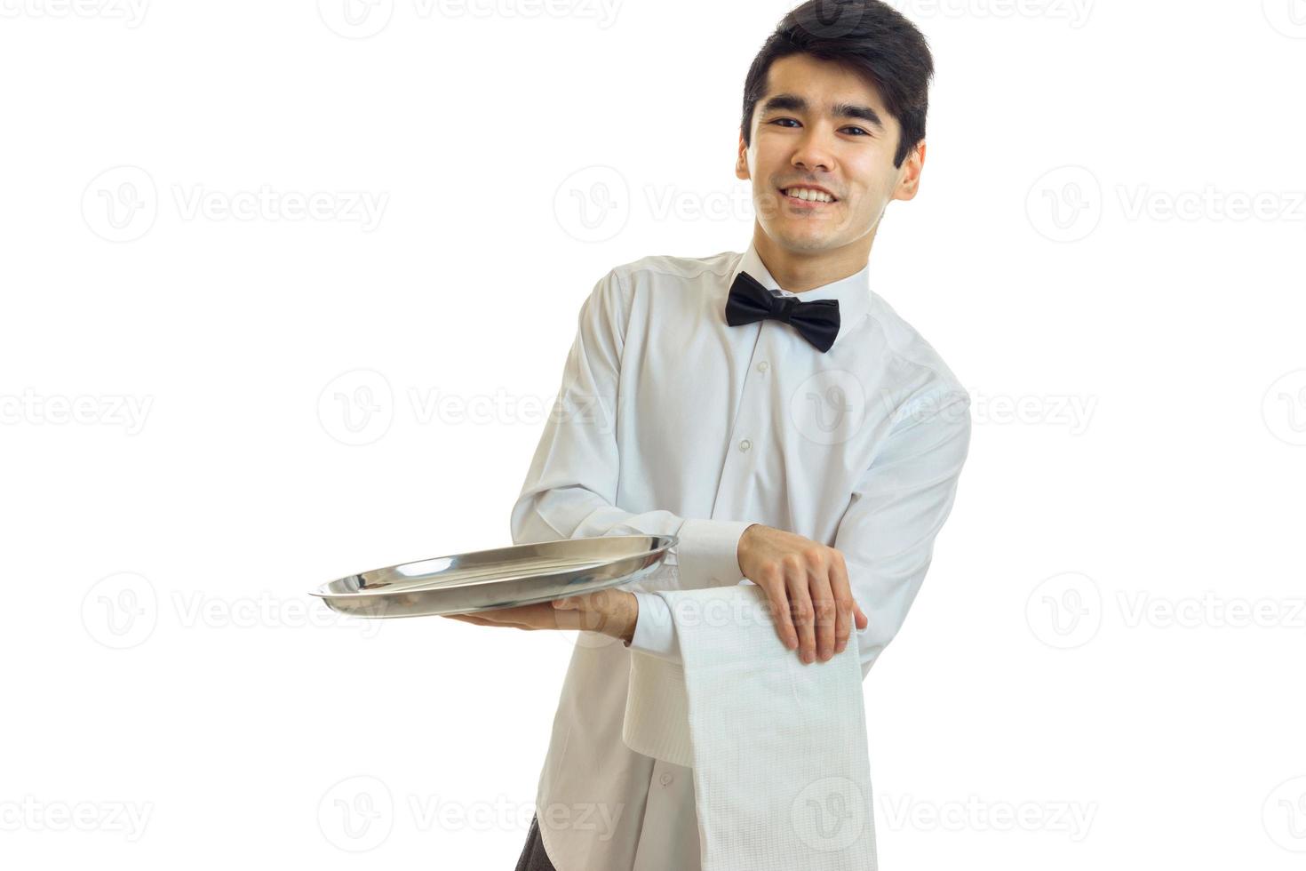 perky young waiter in a white shirt with black bow tie holding a towel and tray for dishware photo