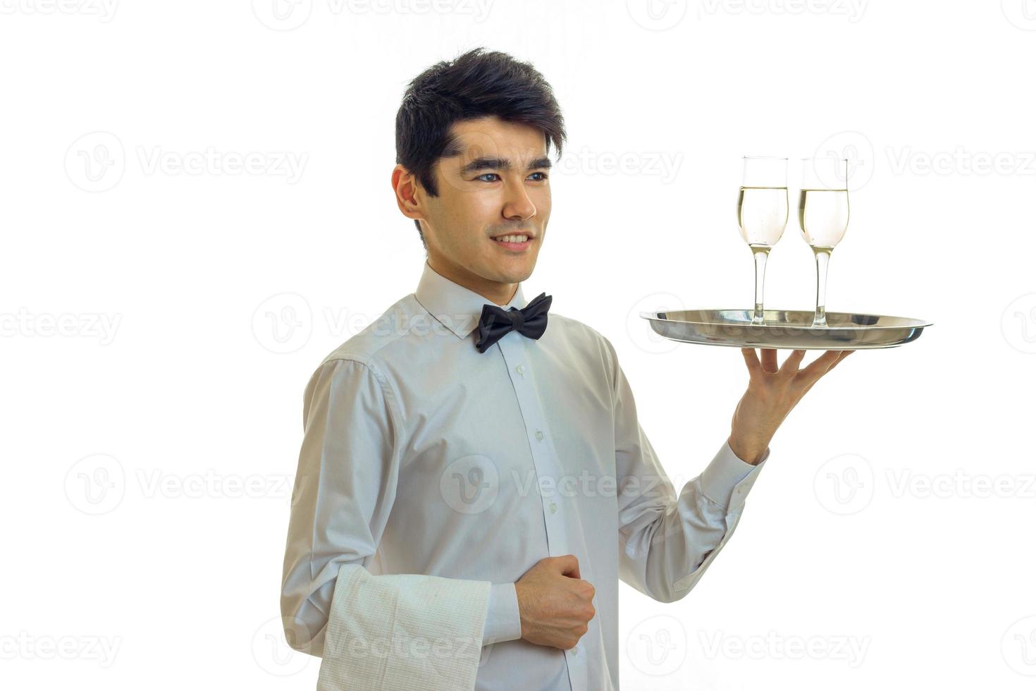 handsome young waiter smiling and holding a champagne glasses on a tray that photo