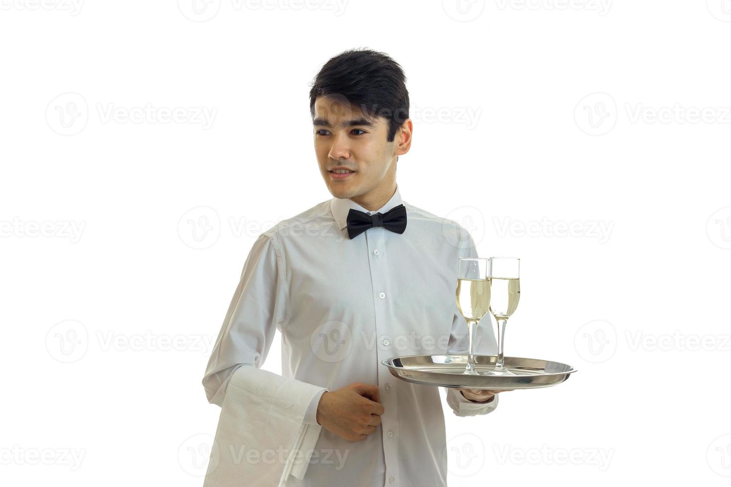 young handsome waiter in a white shirt holding a tray with glasses of champagne photo