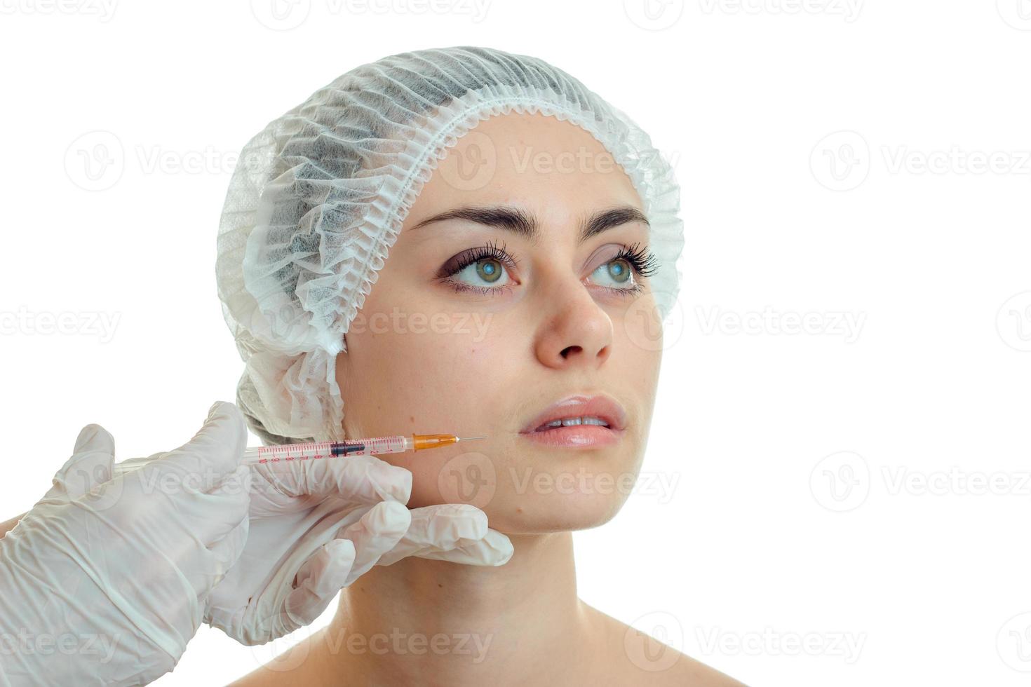 Portrait of a young girl at the doctor who makes an analgesic injection on the face in white gloves close-up photo