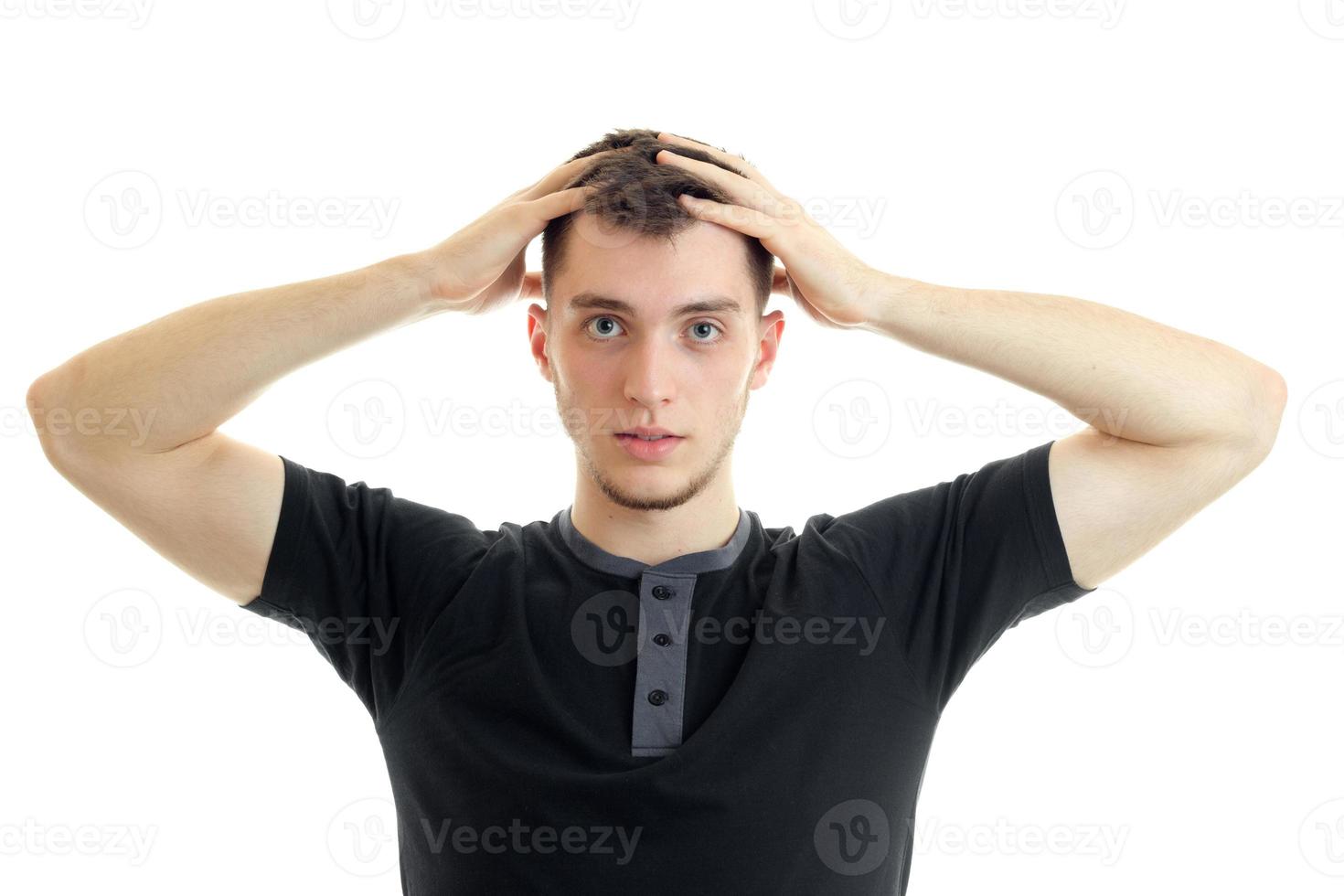 young serious guy kept his hands behind his head and looks directly isolated on a white background photo