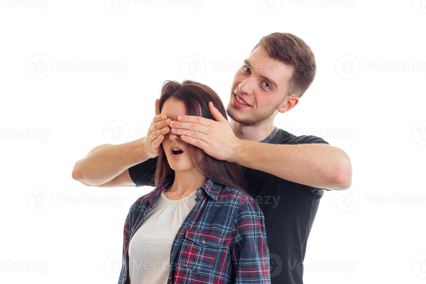 charming young guy came from behind to the girl smiles and closes her eyes hands photo