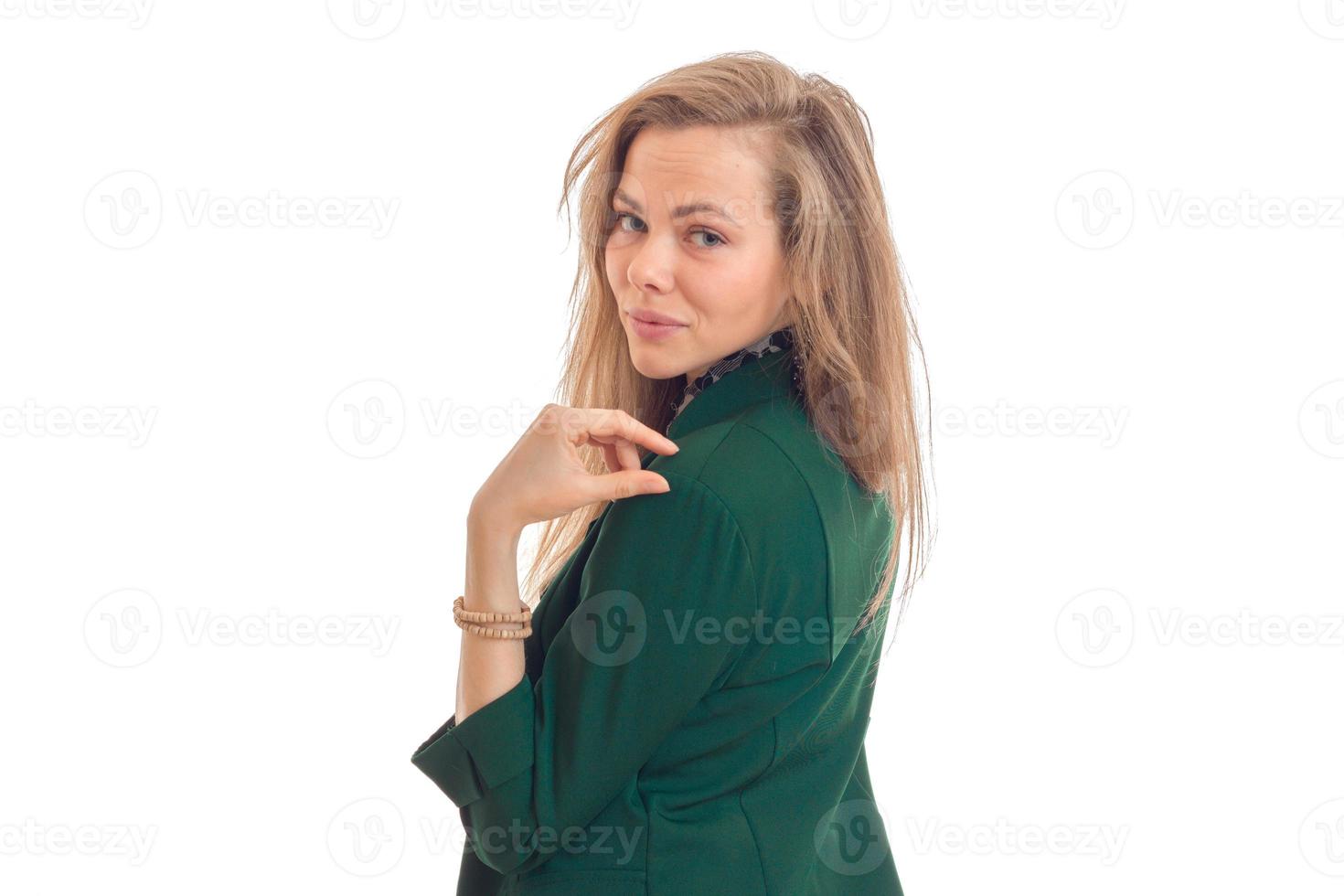 Portrait of a beautiful young blonde in a green jacket that stands sideways and turned her head to the camera photo
