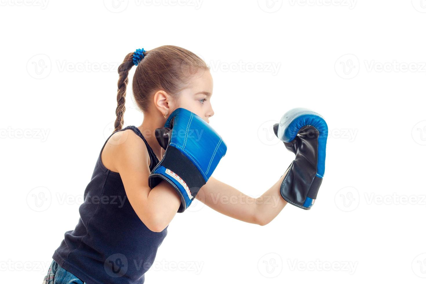 little girl with pigtail stands sideways and make gloves photo