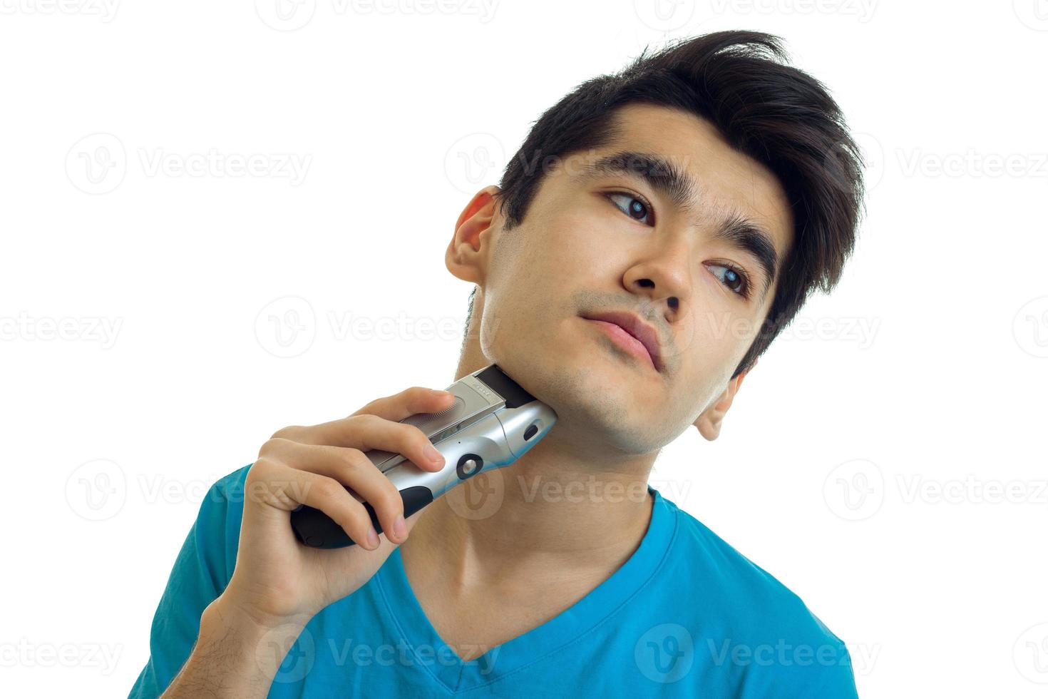 Portrait of a young man who is a luxury bending head looks away and shaves machine photo