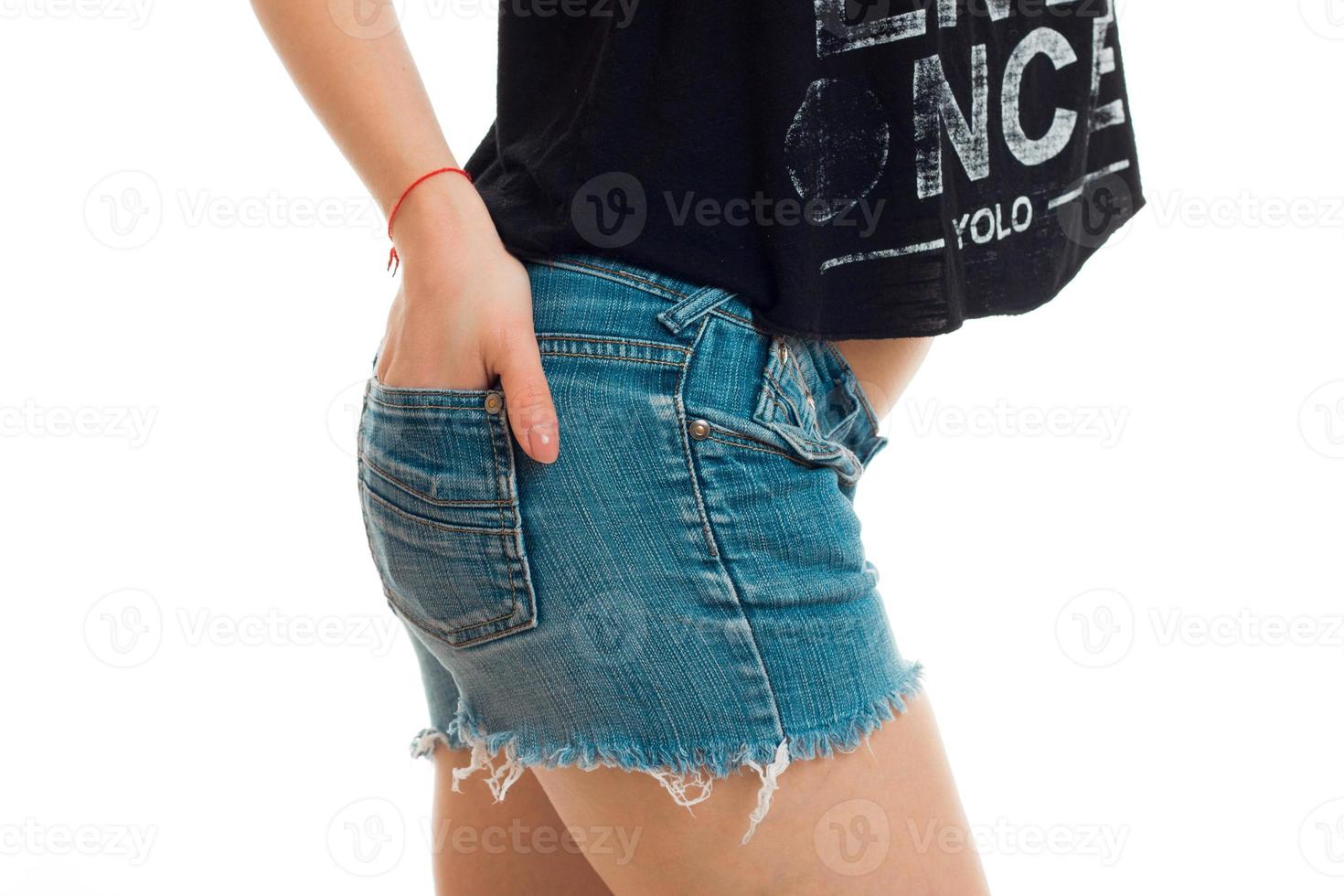 nalgas de mujer en pantalones cortos de mezclilla y un primer plano de una mano en el bolsillo foto
