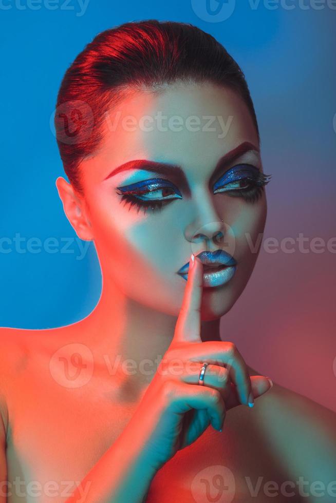Vertical photo of brunette with short hair and make up in red and blue lights