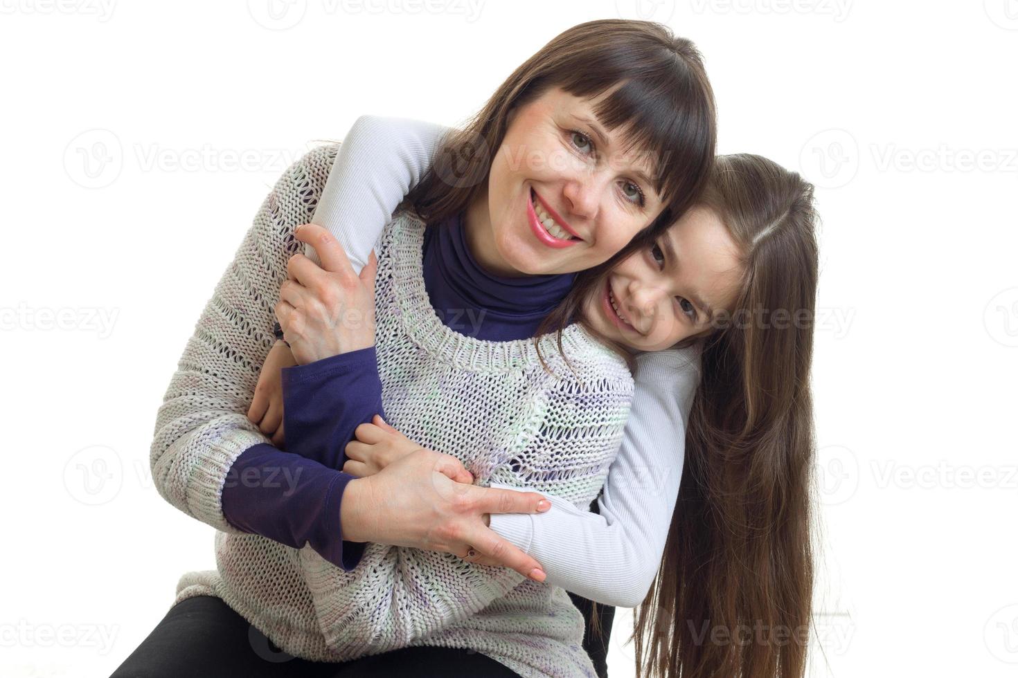little girl hugs her mother from behind and smiles on camera photo