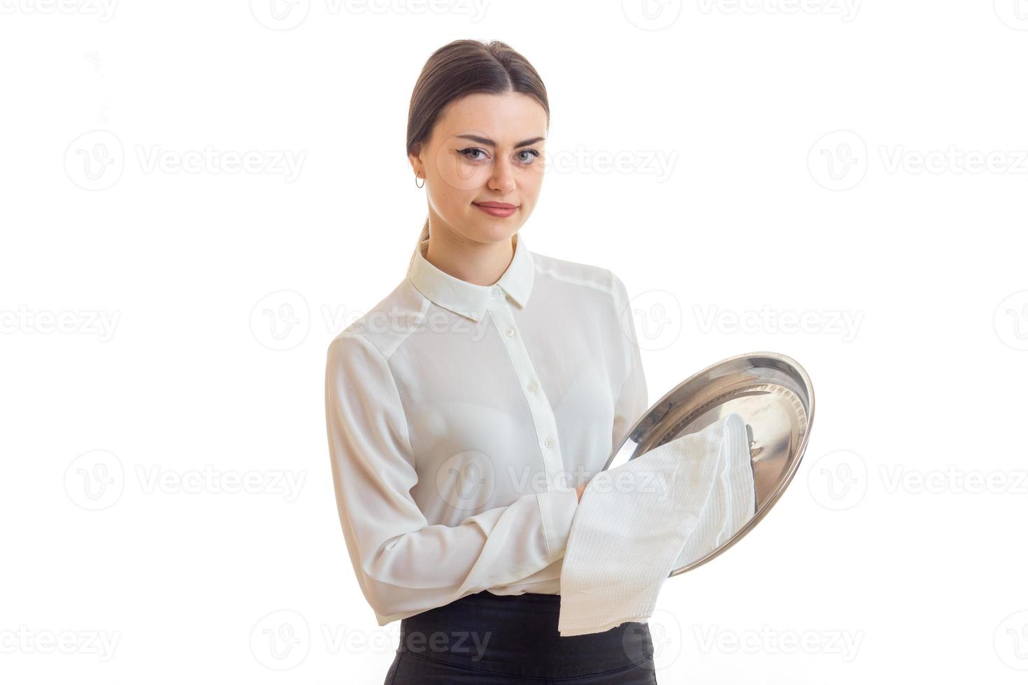 Pretty young waitress cleans a silver trey and looking at the camera photo