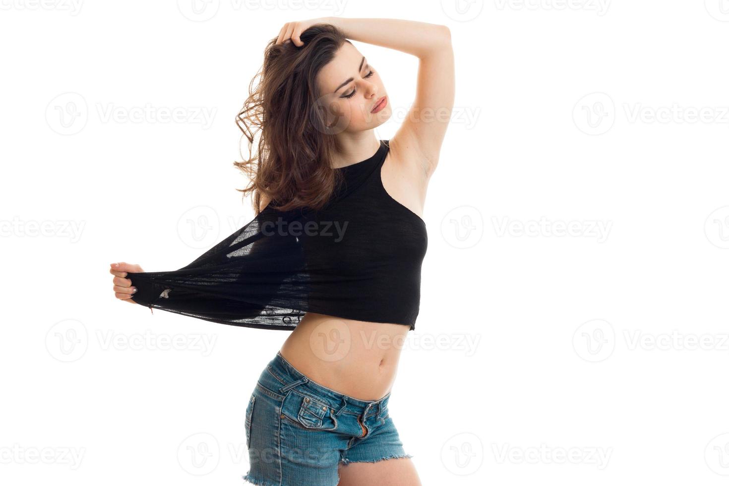 Sensual young brunette with closed eyes take off a black t-shirt photo