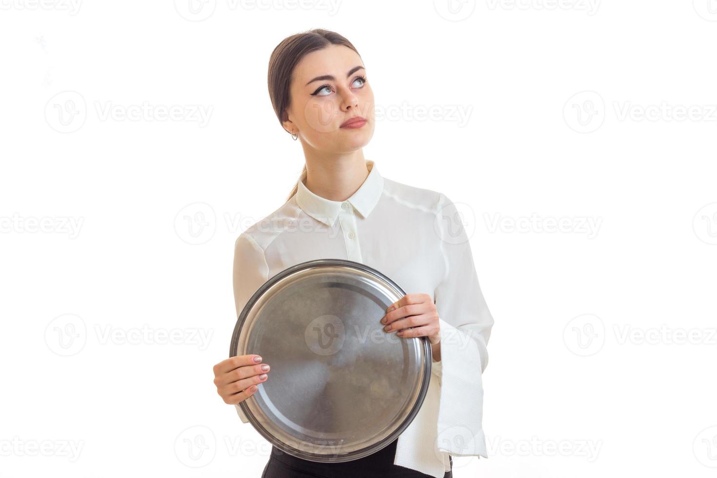 beautiful thoughtful girl-waiter holds a large round tray and looking up photo