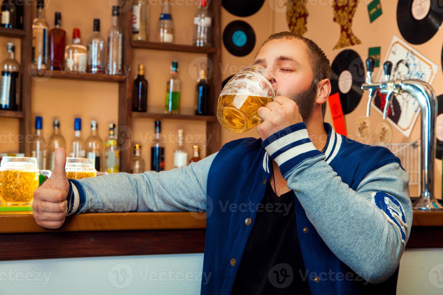 chico adulto en un bar bebiendo un delicioso vaso de cerveza ligera foto