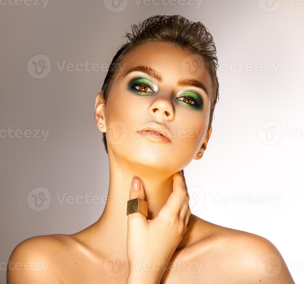 hermosa chica adulta con bonitos colores verdes maquillados en el estudio mirando a la cámara foto