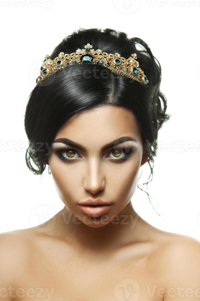 Sexual young brunette with perfcet creative hairstyle and crown on head looking at camera photo