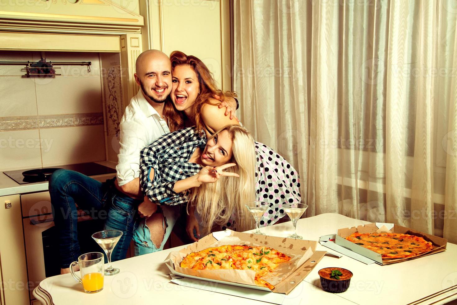 Horizontal portrait of fun three people at a party with pizza and alcohol photo