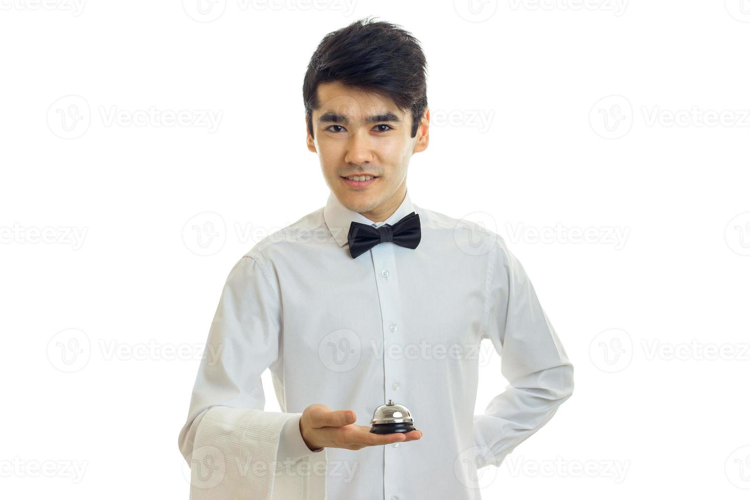 chic, charming waiter's shirt and with a butterfly on his neck looks ahead and holds in his hand Bell photo