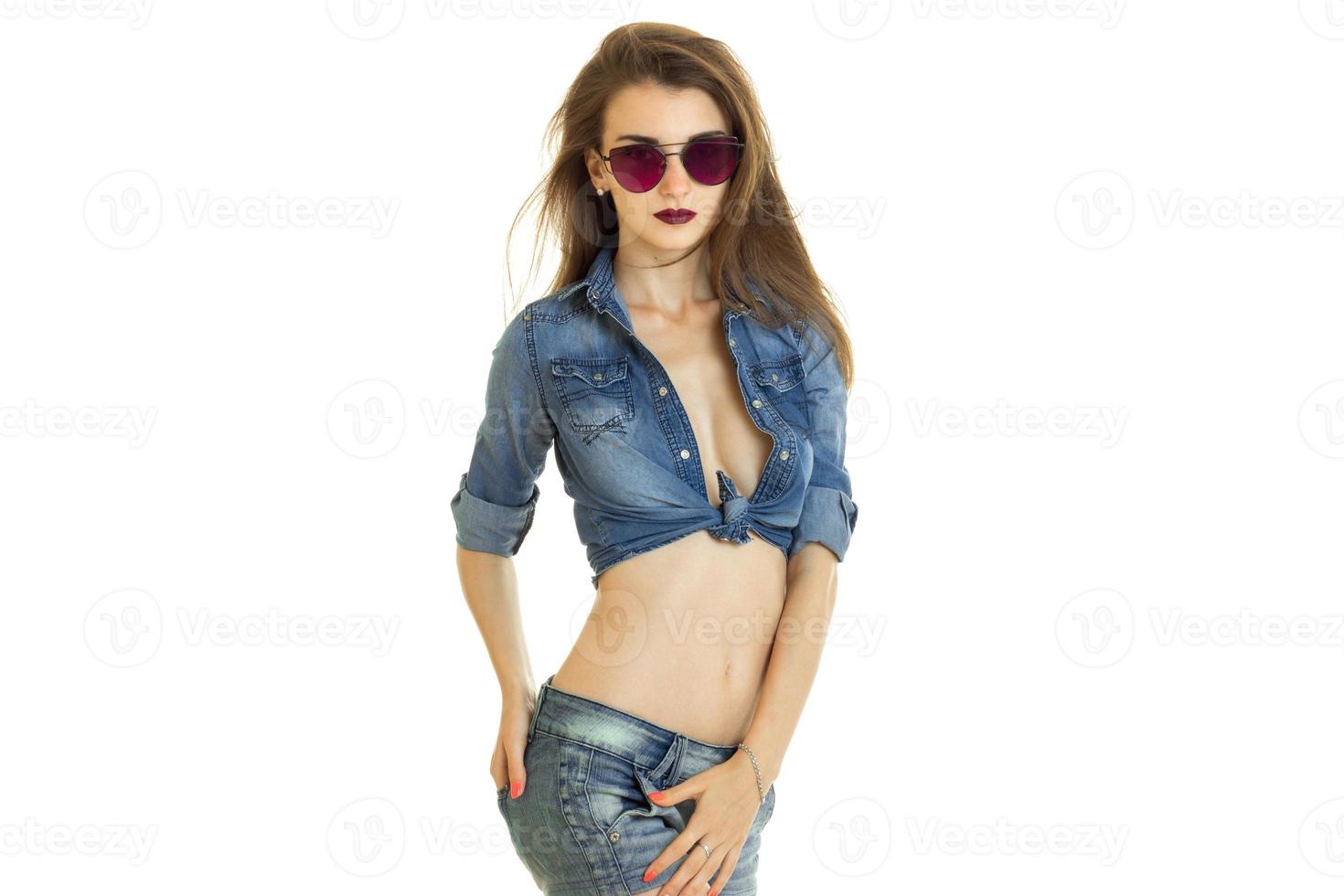 young glamour girl in bright glasses and jeans costume poses on camera photo