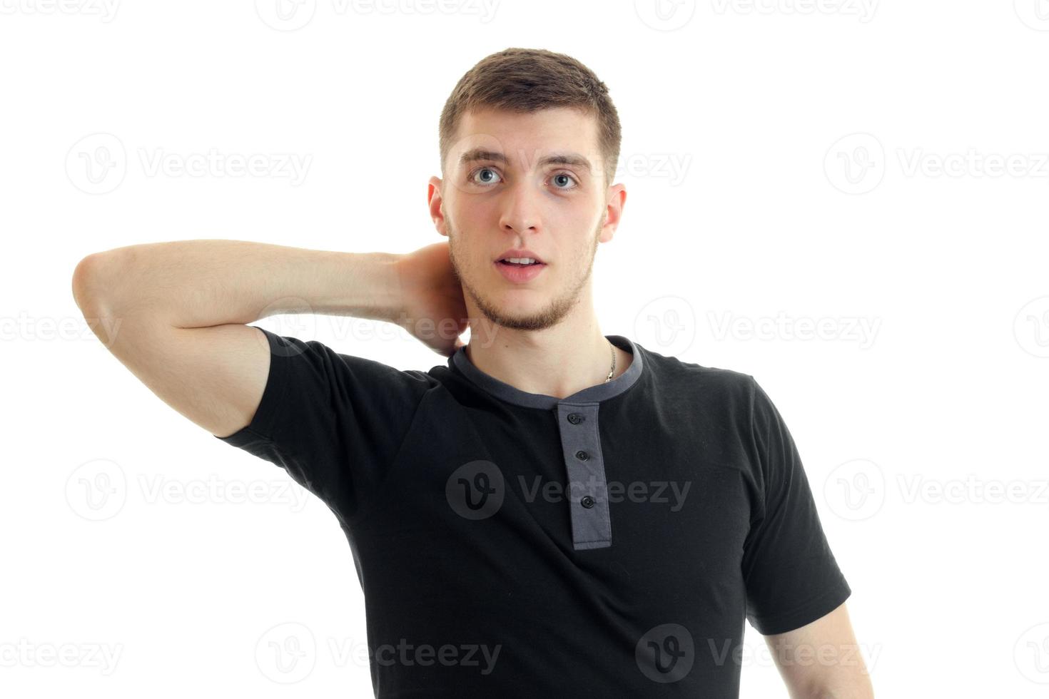 Surprised young man in black t-shirt looking away in studio photo