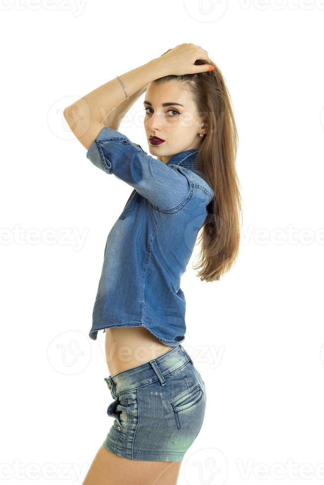 vertical portrait of beautiful fashion girl in denim shorts and a shirt that posing in the Studio photo