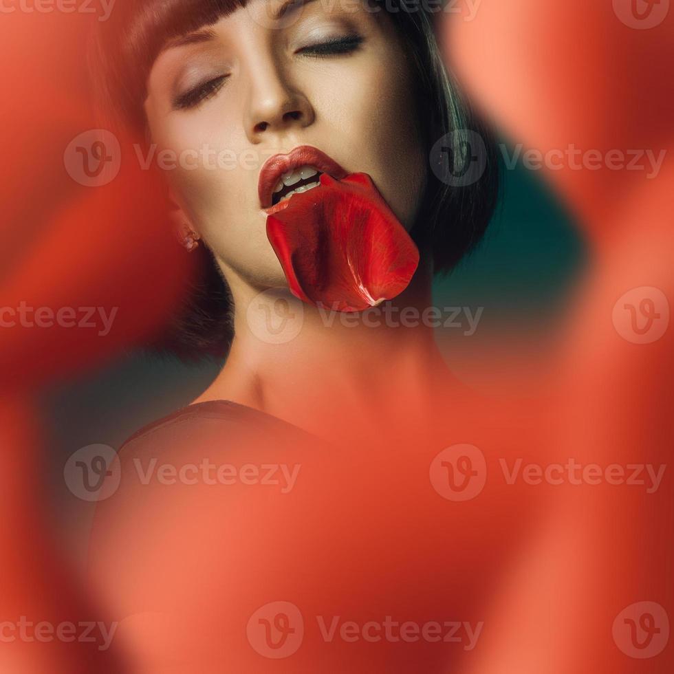 Sensual female behind red rose in studio photo