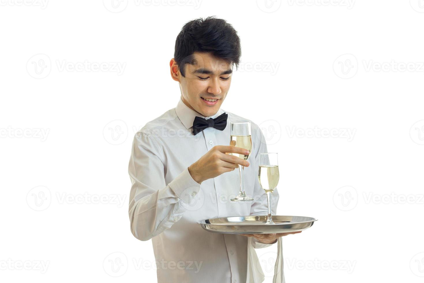 feliz joven camarero en uniforme con dos copas de vino en bandeja de plata sonriendo foto