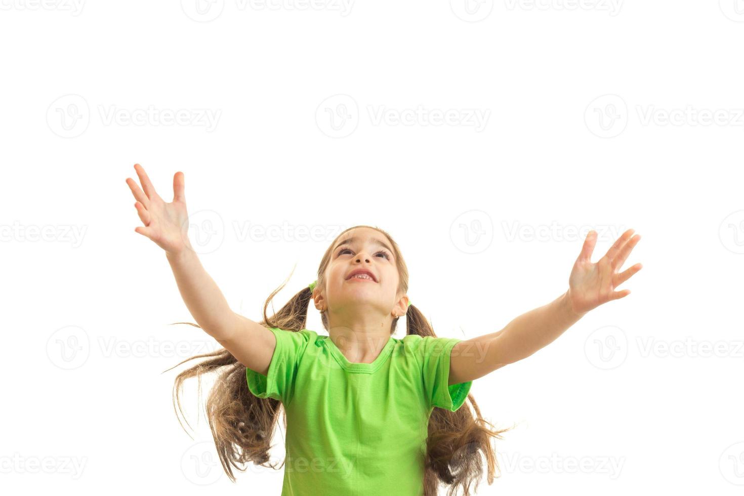 Cheerful little girl in green shirt with hands up photo