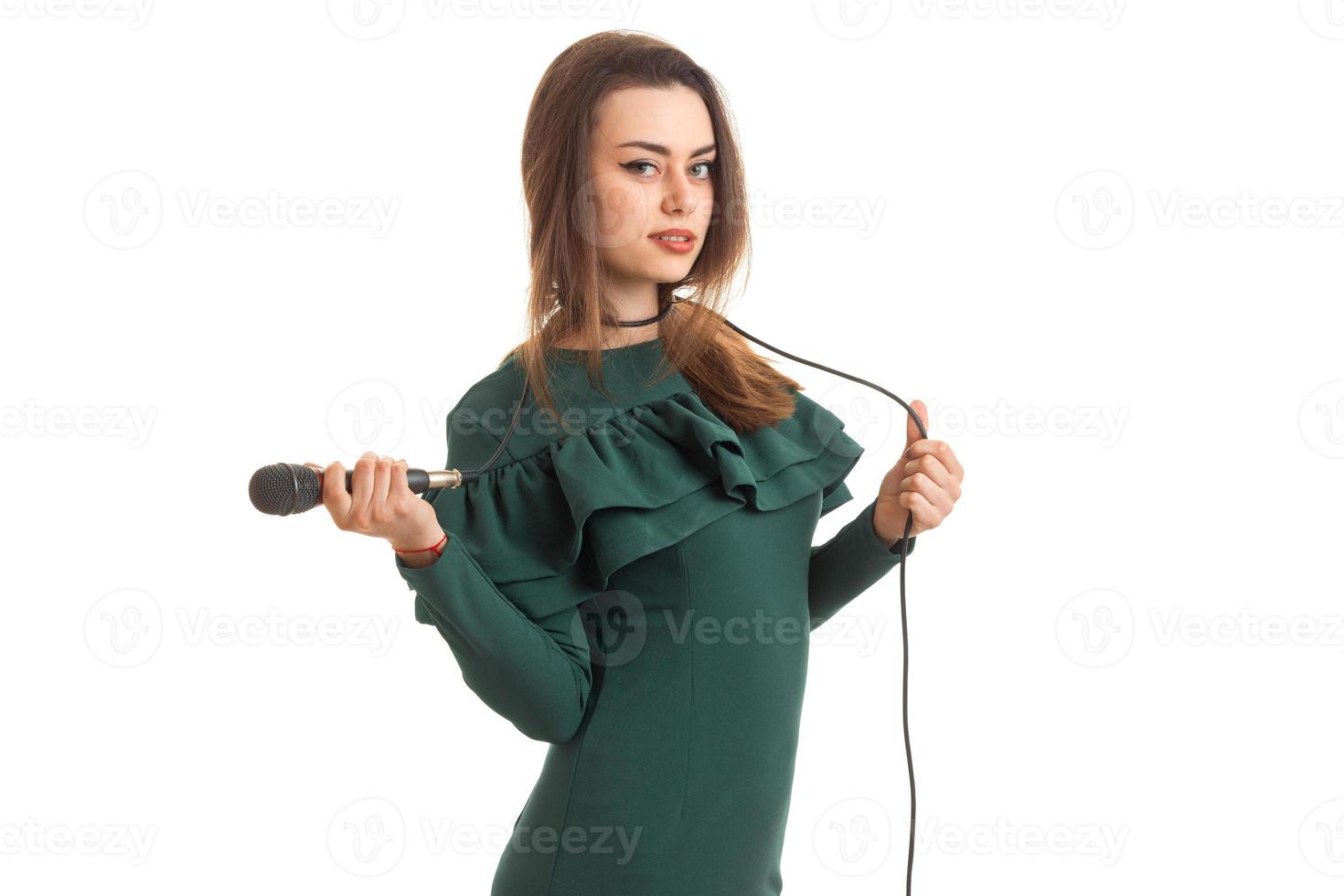 hermosa mujer morena en elegante vestido verde con micrófono foto