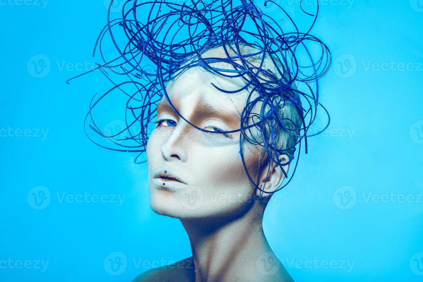 Attractive female with creative body art and hairstyle on blue background photo