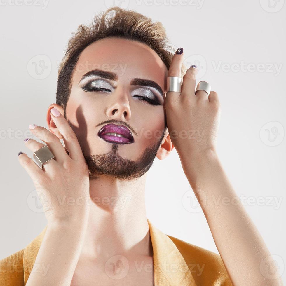 hombre sensual con maquillaje y ojos cerrados en estudio foto