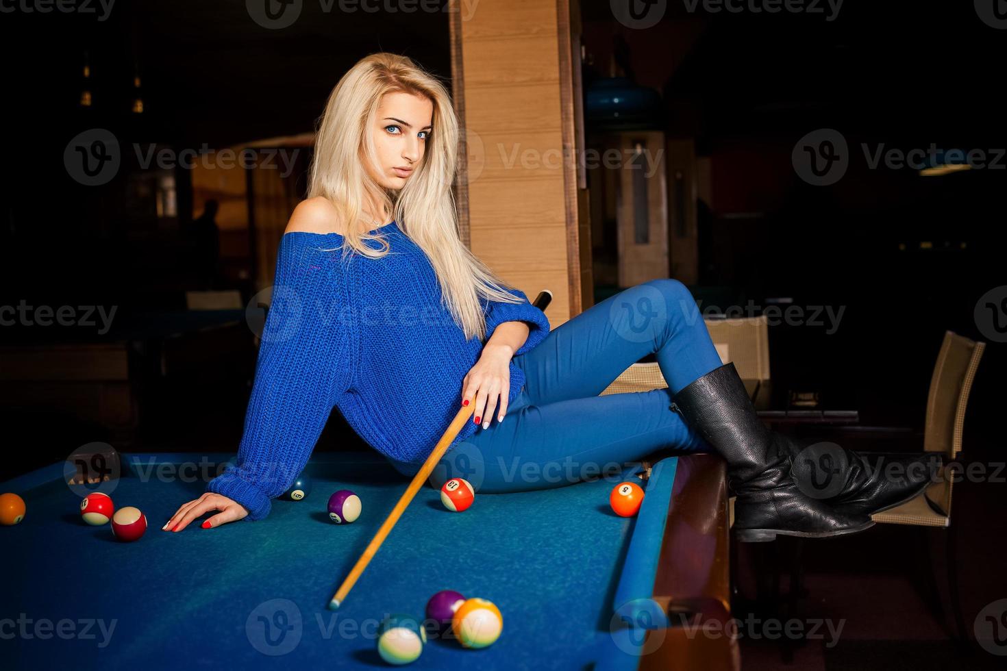 Sexual blonde lady posing on billiard table with the cue photo