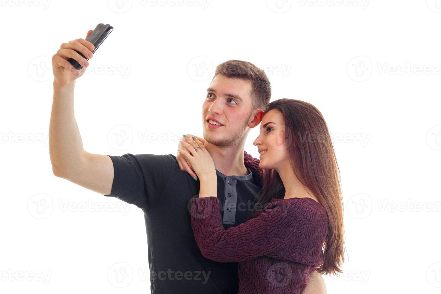 a charming guy and cute girl hug and make photo on phone close-up