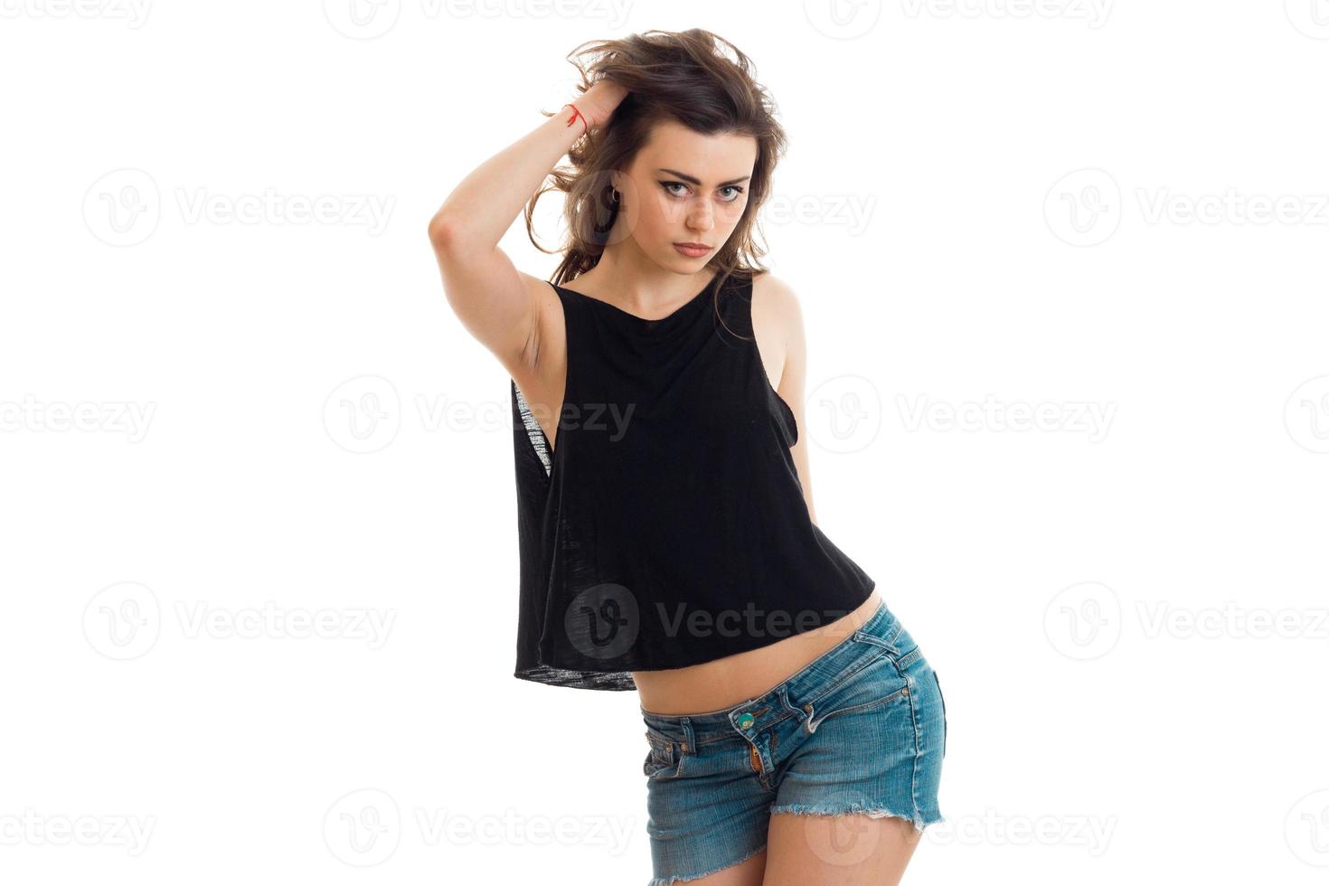 adolescente morena en pantalones cortos de mezclilla y una camiseta negra posa sexy en la cámara foto