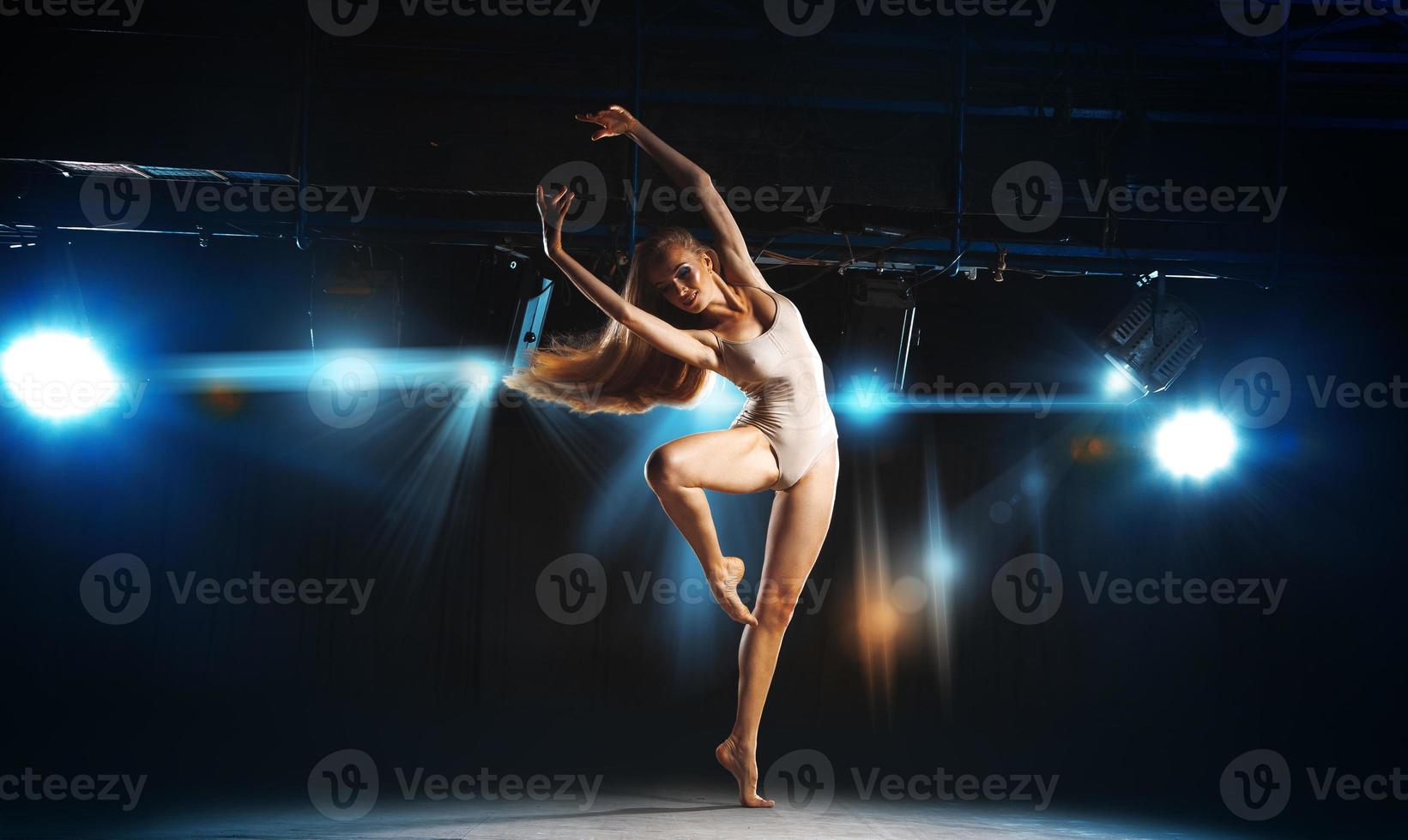 Charming young blonde ballet dancer posing on stage photo