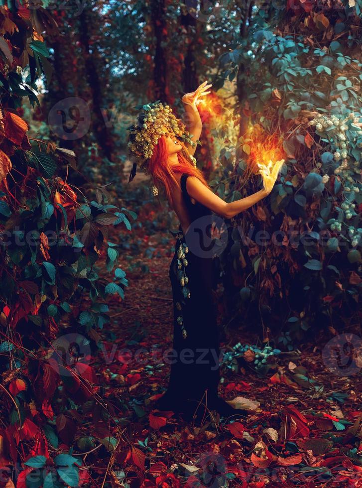 awesome young witch conjures in the forest photo