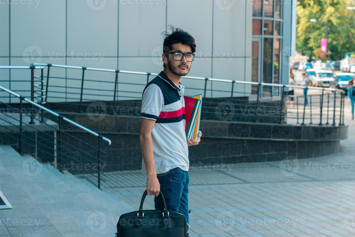 young brunette student boy with bag and books in his hands photo