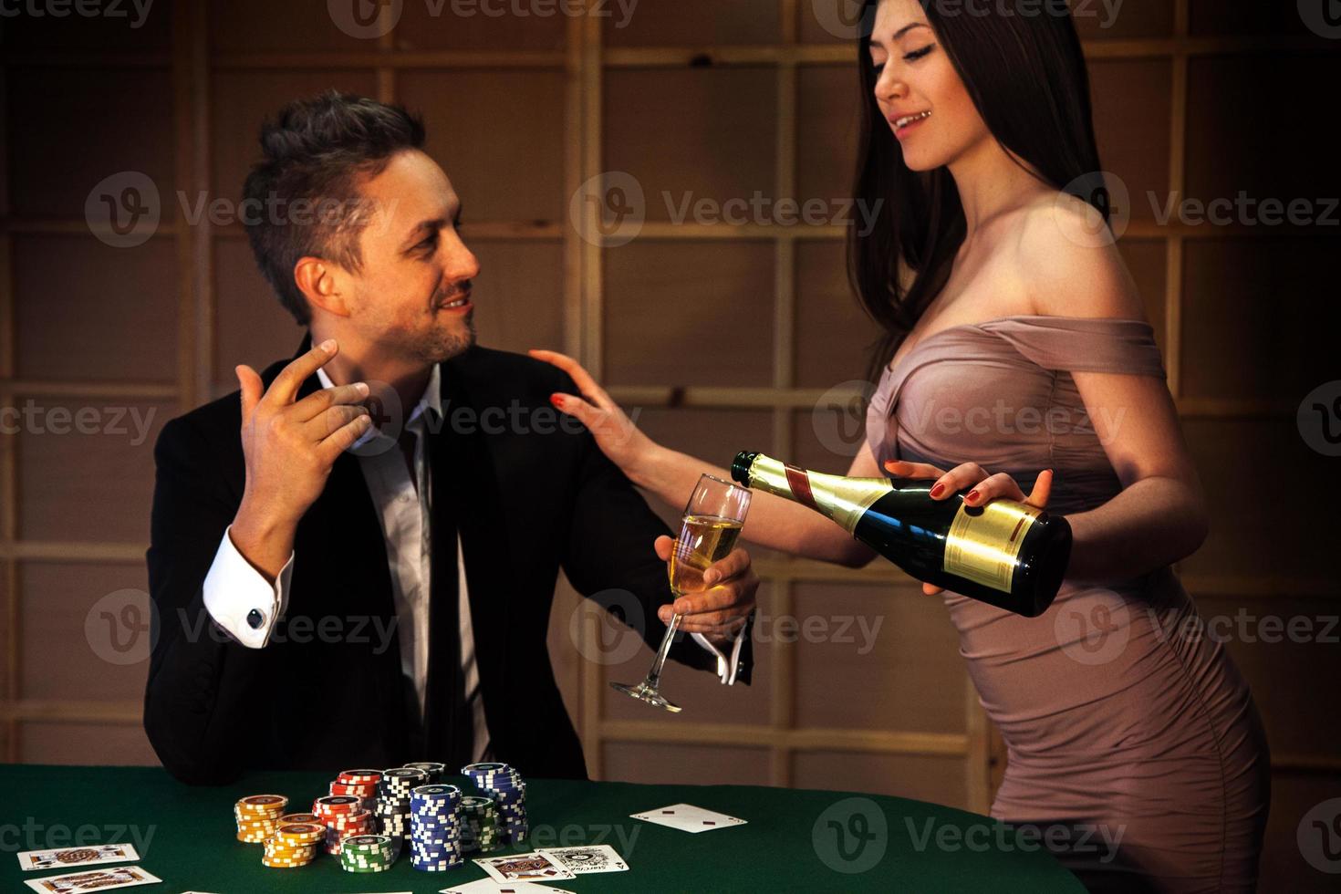 beauty guy flirting with a girl who pours champagne at the poker table photo