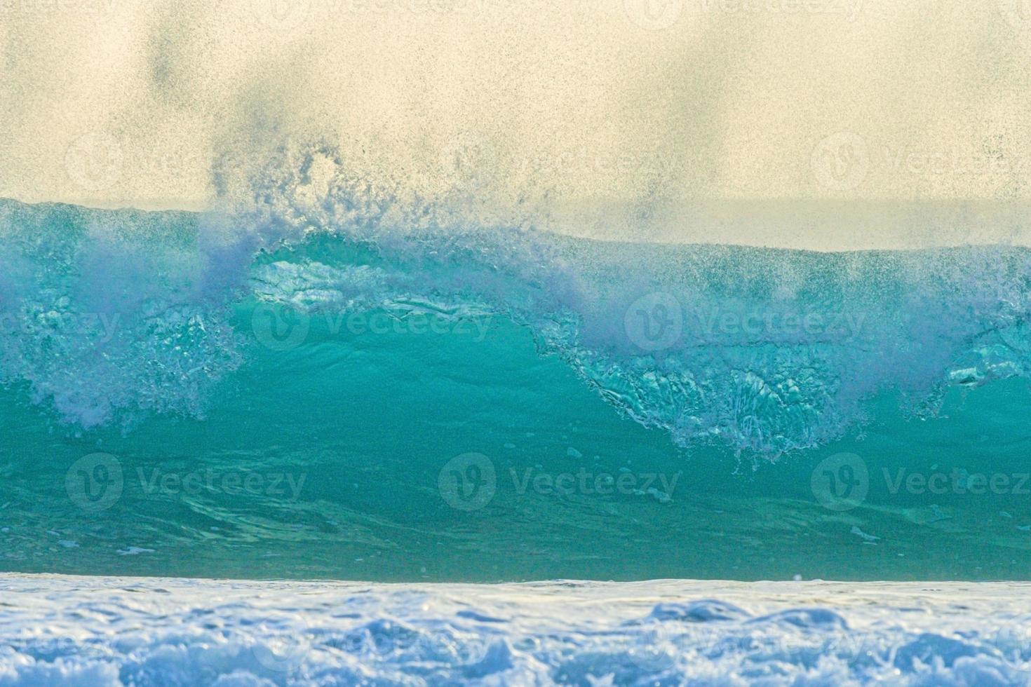 Image of wave breaking on the beach with flying spray and turquoise color photo