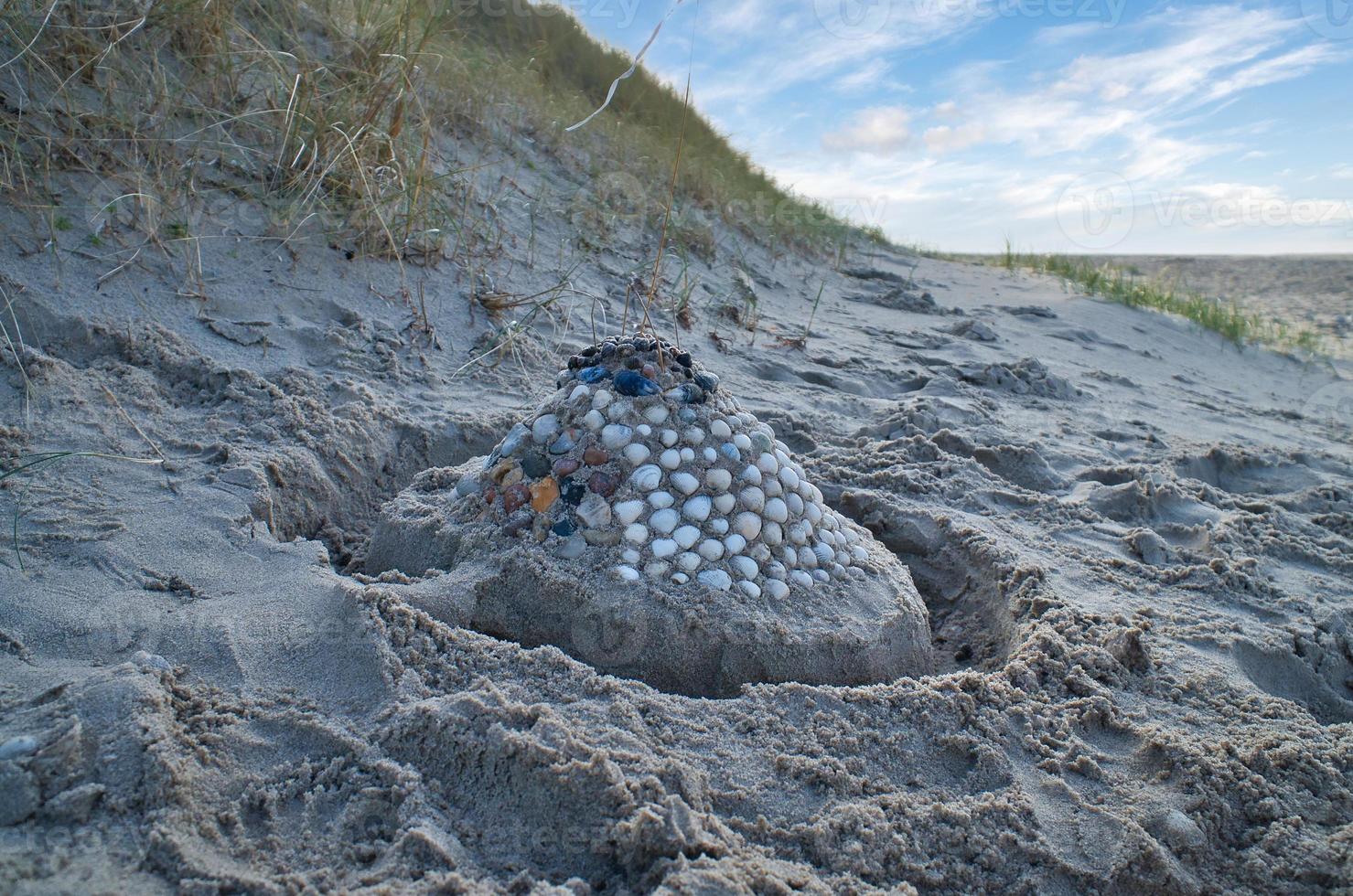 Sand castle with shells and sand. Moat around the castle in front of dunes. Denmark photo